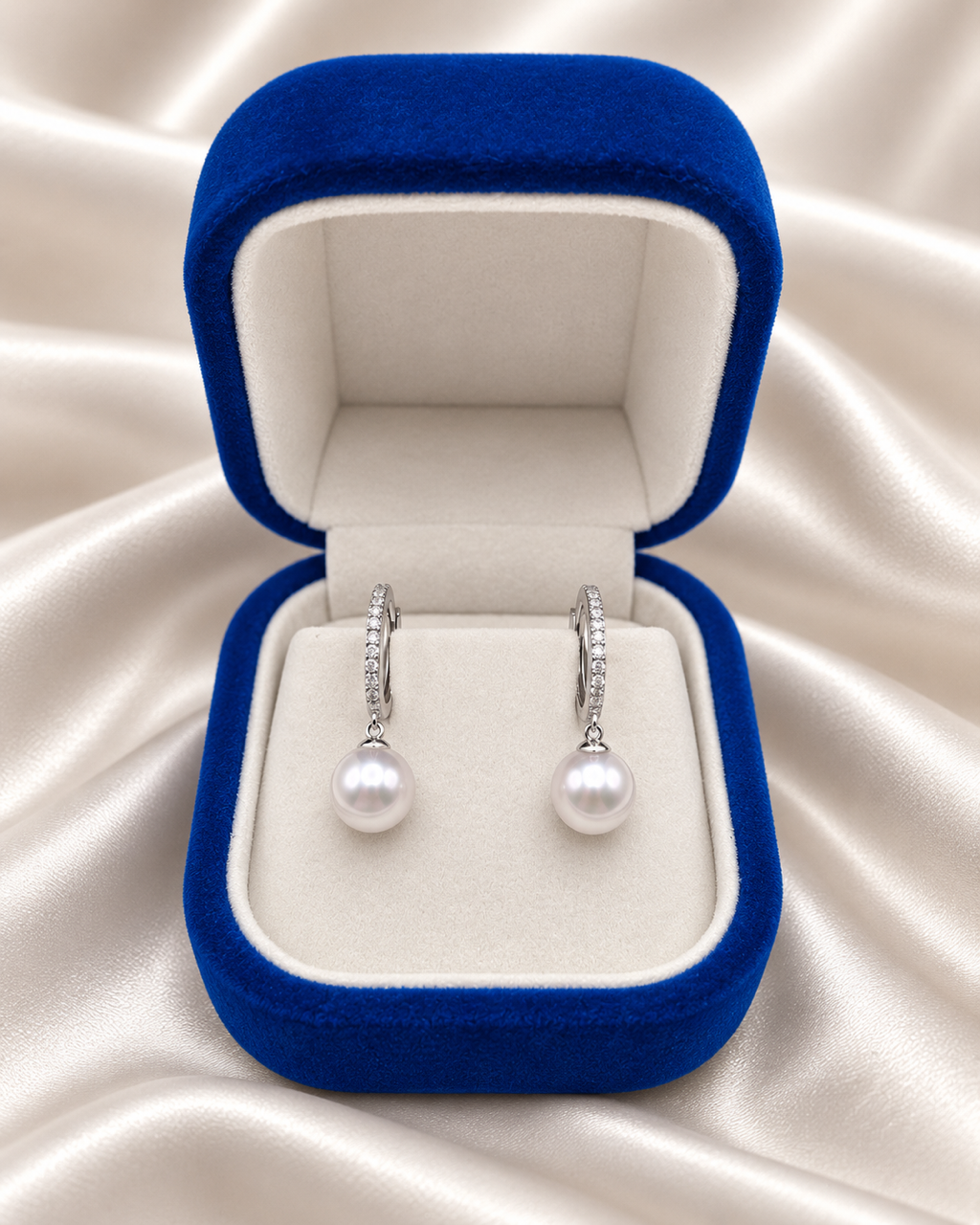 The sterling silver pearl huggie earrings inside a navy velvet Lespéra jewelry box